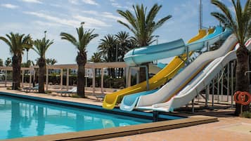 Une piscine dotée de plusieurs toboggans et de chaises longues.