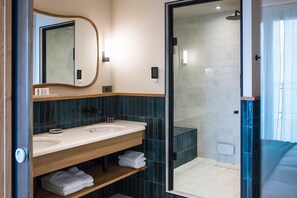 Un baño moderno con dos lavamanos, un espejo grande y una zona de ducha con mampara de vidrio.