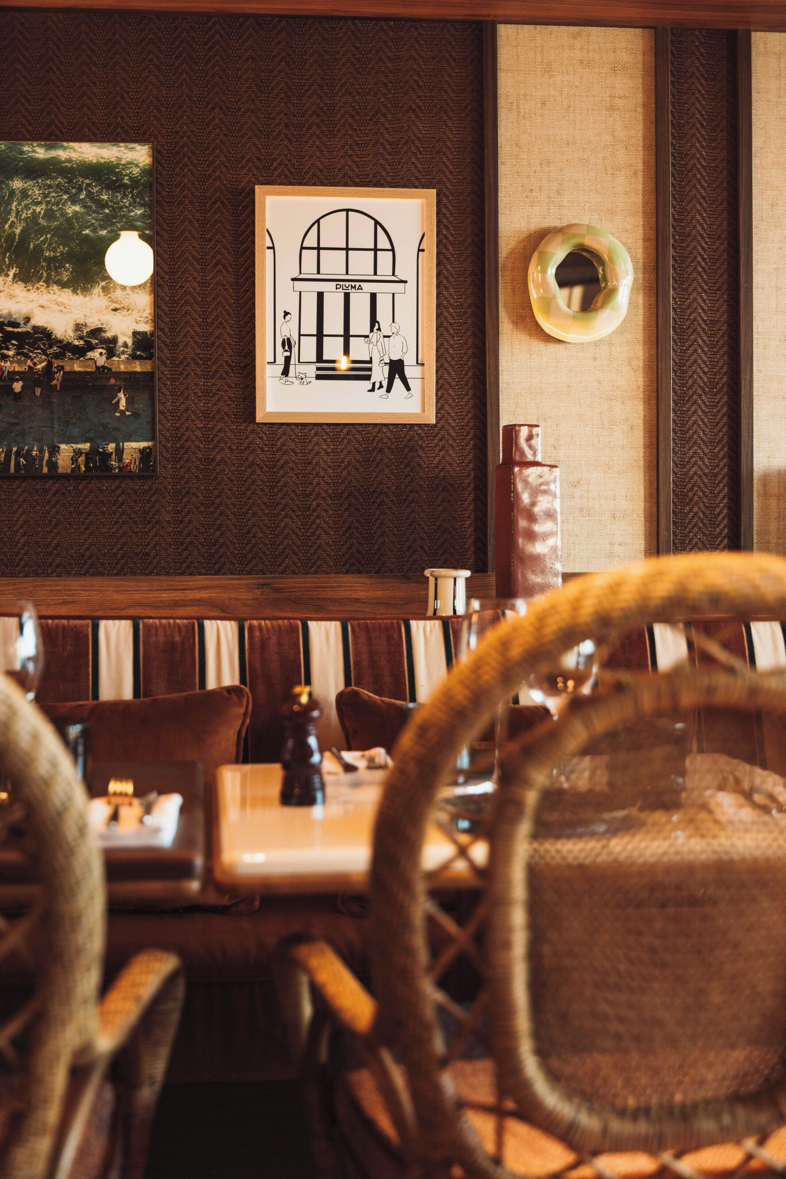 Interno di un ristorante con mobili in legno, un disegno architettonico incorniciato e un elemento decorativo a parete.