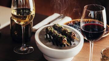 Una mesa de comedor con un bol de comida, dos copas de vino y un plato de comida.