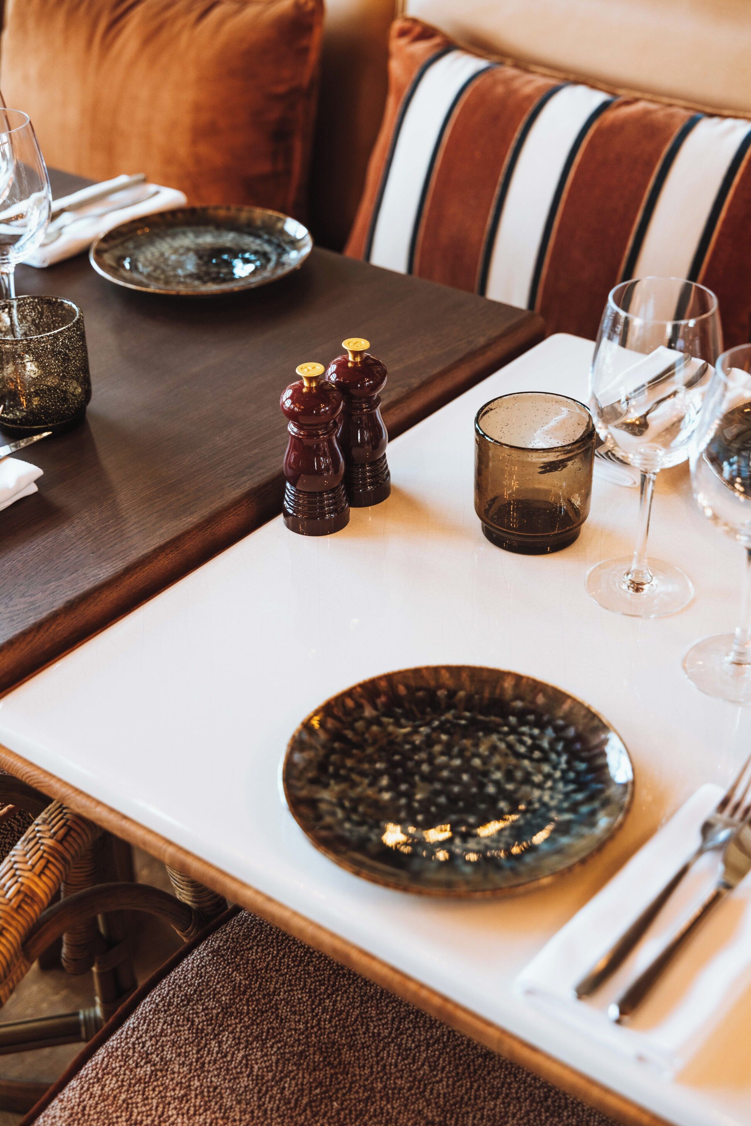 Een eettafel gedekt met borden, glazen en zout- en peperstel.