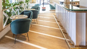 Een moderne hotellobby met een centrale bar, een zithoek en uitzicht op buiten.
