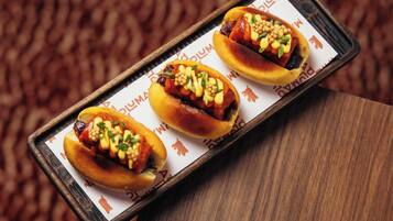 A tray with three hot dogs on a wooden surface.
