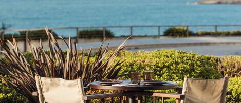 A table and chairs set outdoors with a view of the ocean.