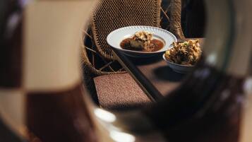 A checkered floor pattern, a woven chair, and a table with a plate of food.
