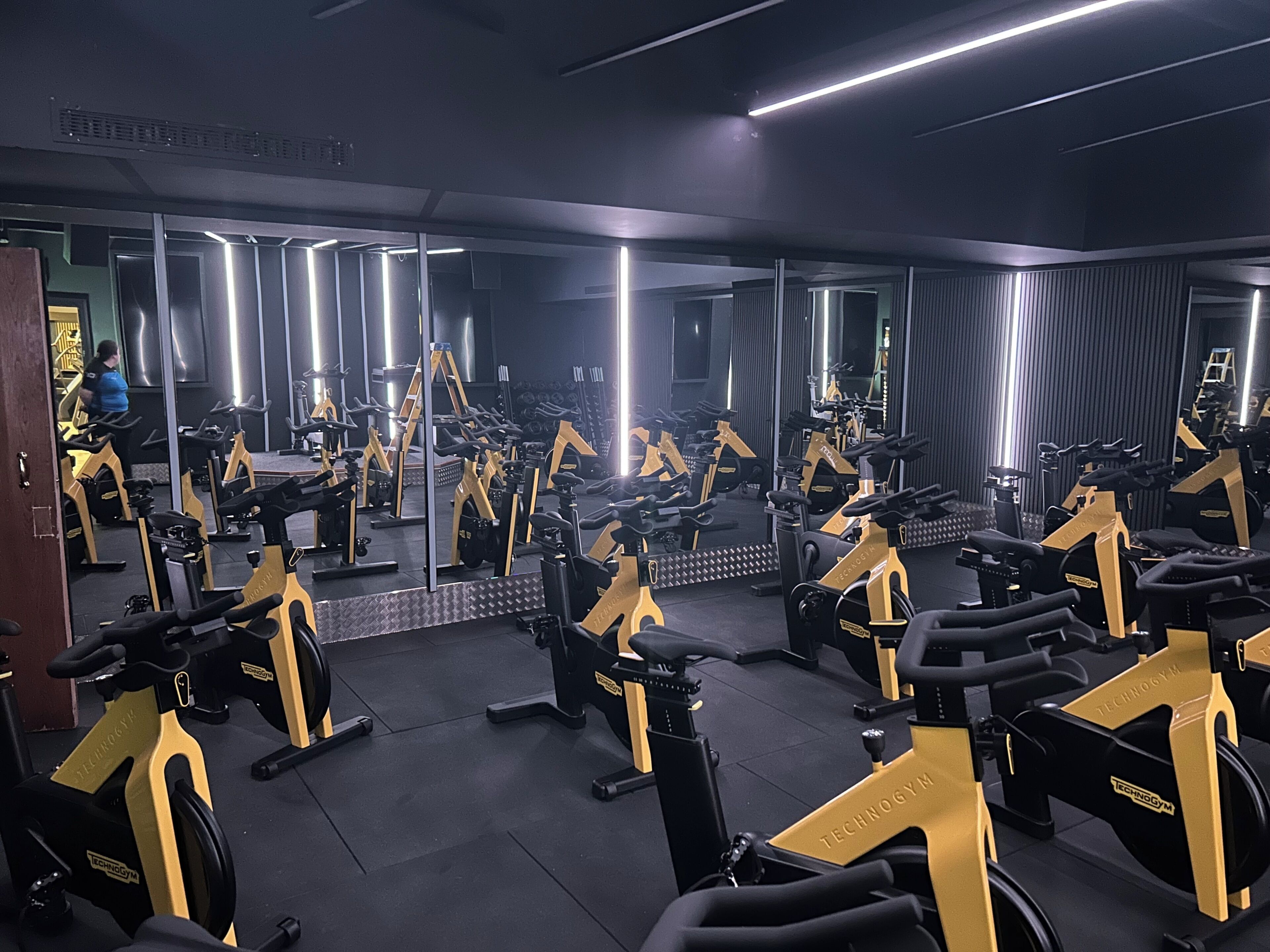 Un gimnasio con varias bicicletas estáticas y espejos en las paredes.