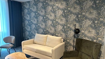 Een woonkamer met een bank, fauteuil en een lamp.