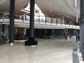 Un vestíbulo amplio con techo alto, una recepción, una zona de estar y una escalera que conduce a los pisos superiores.