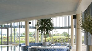 An indoor swimming pool with a blue mosaic floor and a central fountain. - Pillo Hotel & Leisure Club (Ashbourne)