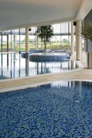 Una piscina interior con suelo de mosaico azul y una fuente central.