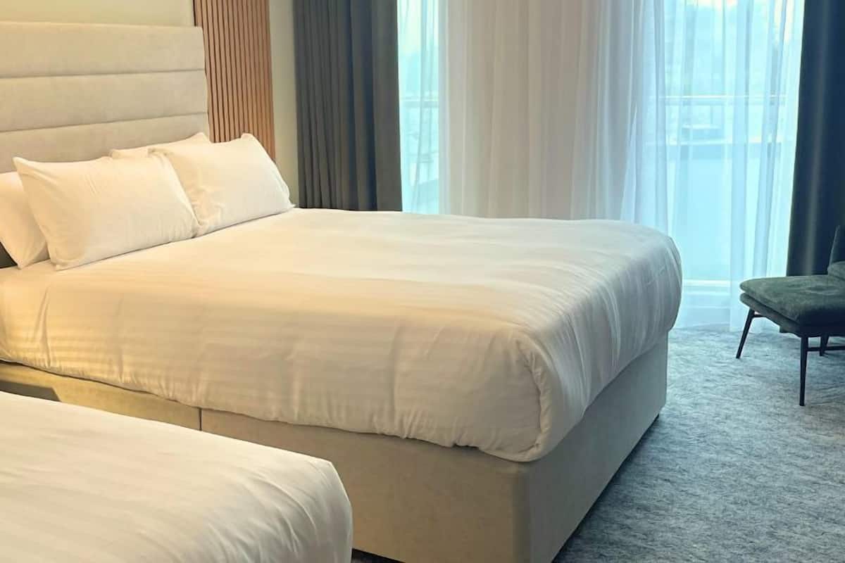 Una habitación de hotel con una cama grande, una mesita de noche y una silla.