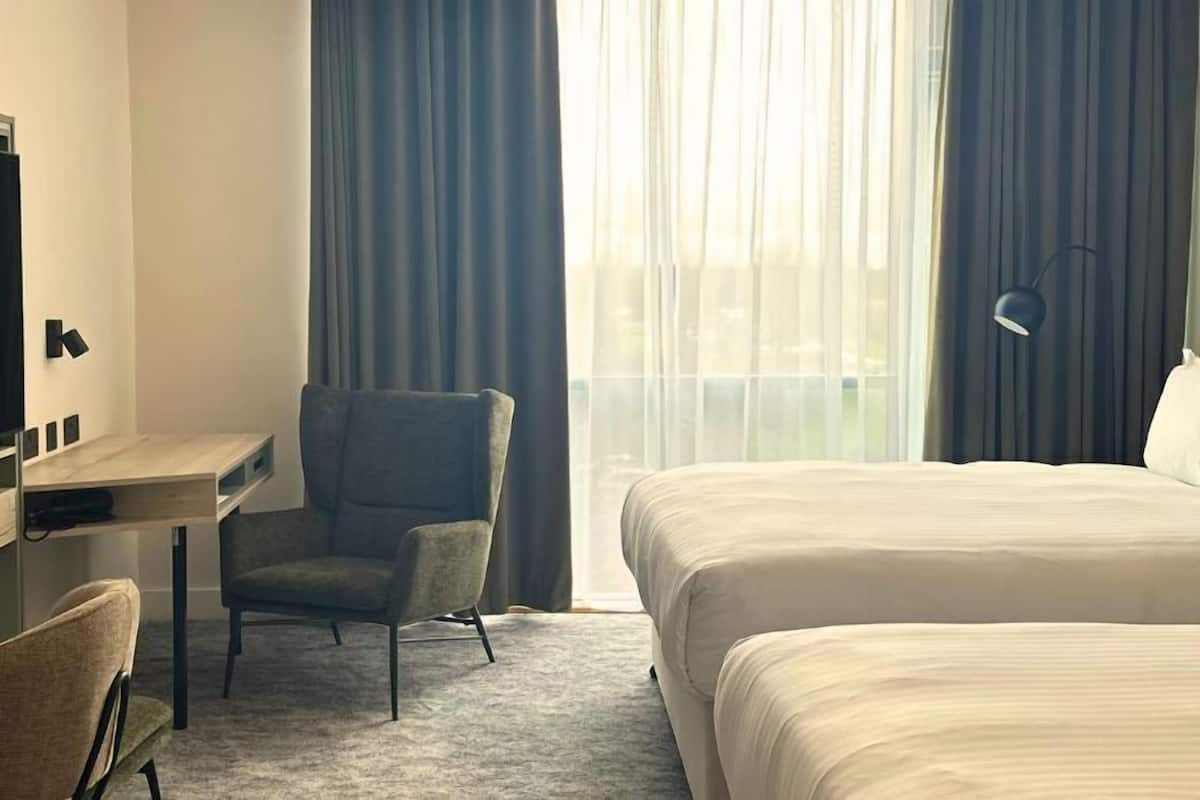 Una habitación de hotel con cama, escritorio, silla y televisor.