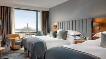A hotel room with two beds, a view of the city, and a large window.