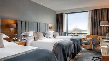 Ein Hotelzimmer mit zwei Betten, einem Schreibtisch, einem Stuhl und einem großen Fenster mit Blick.