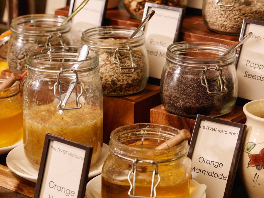 A display of jars with labels such as 'Orange Marmalade' and 'Poppy Seeds'.
