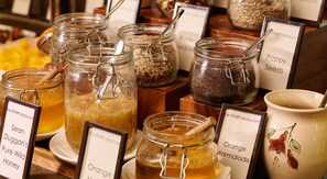 A display of jars with labels such as 'Orange Marmalade' and 'Poppy Seeds'.