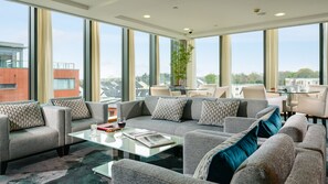 A modern living room with a sectional sofa, a glass coffee table, and a dining area with chairs and a table. - Limerick Strand Hotel (Limerick)