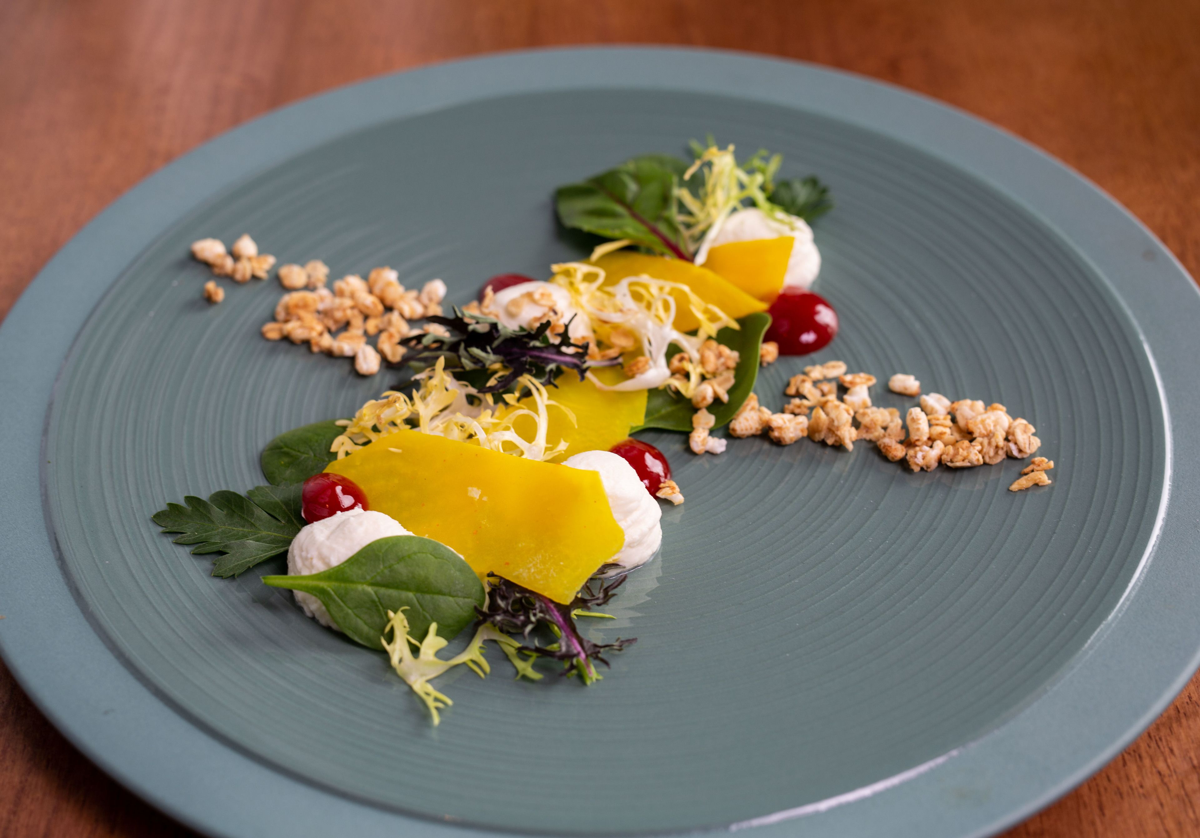 A plate with a variety of food items including vegetables, nuts, and a cherry.