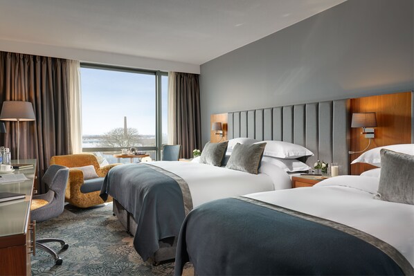 A hotel room with two beds, a desk, a chair, and a view of the city. - Limerick Strand Hotel (Limerick)