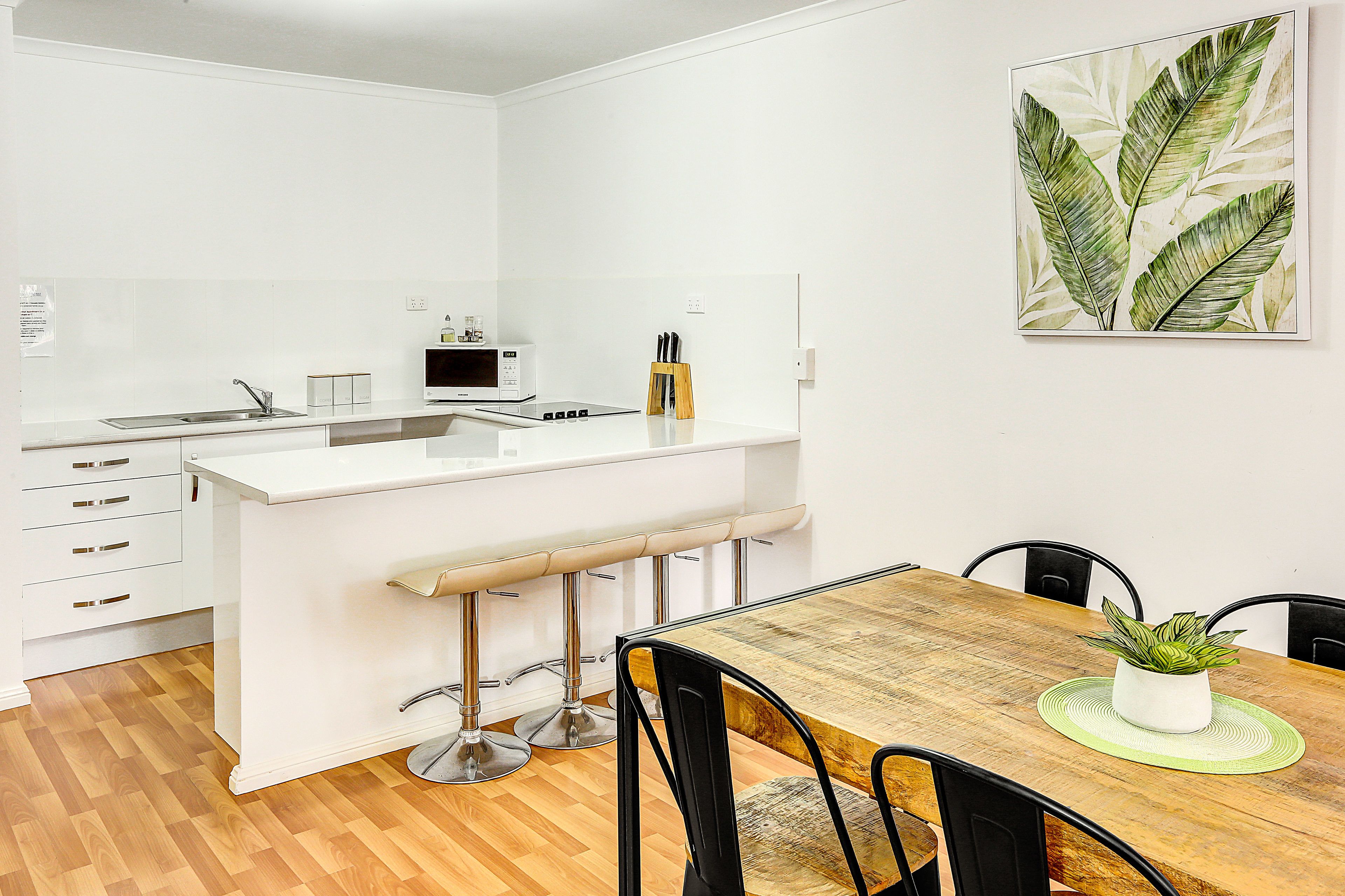 A modern kitchen with a white countertop, a built-in microwave, and a knife block.