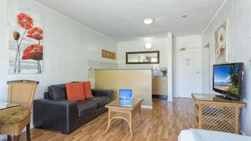 Una sala de estar con un sofá, una mesa de centro de vidrio, un televisor y un cuadro en la pared.