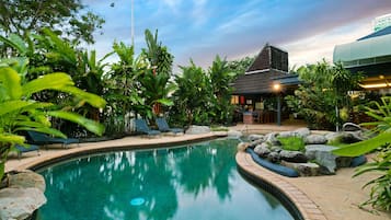 Una piscina al aire libre, sillones reclinables de piscina