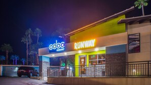 Ein Hotel namens 'Coco Resort' mit einem Schild 'Runway', Palmen und einem Parkplatz.