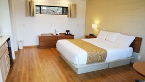 Ein Hotelzimmer mit einem Bett, Nachttisch, Lampe und einem Fenster mit Vorhängen.