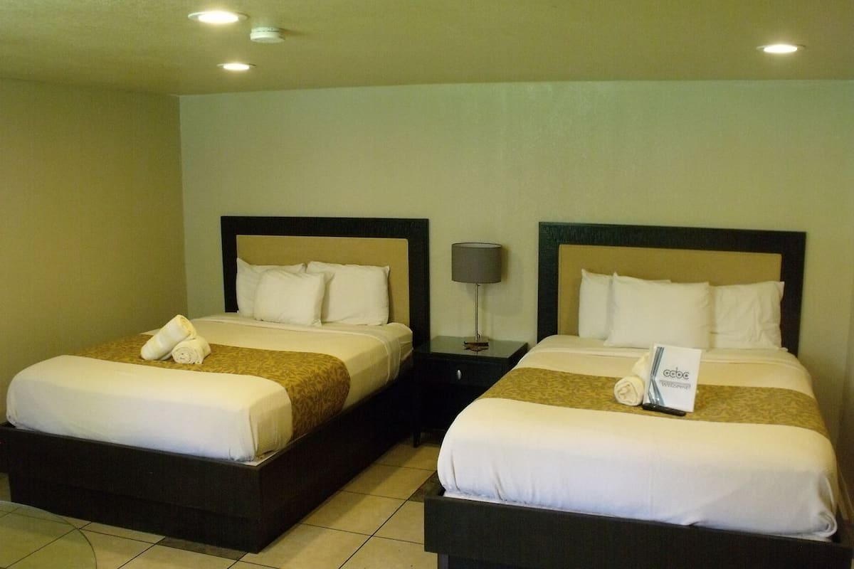 Two single beds with headboards, a nightstand with a lamp, and a folded towel on each bed.