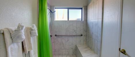 A bathroom with a shower, a window, and a towel rack with towels.
