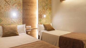 Habitación de hotel con dos camas, una pared de acento de madera, papel tapiz estampado y una mesita de noche con lámpara.