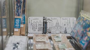 Una exhibición de artículos de papelería con temática de Barcelona, incluyendo postales y cuadernos, con ilustraciones de los monumentos de la ciudad.