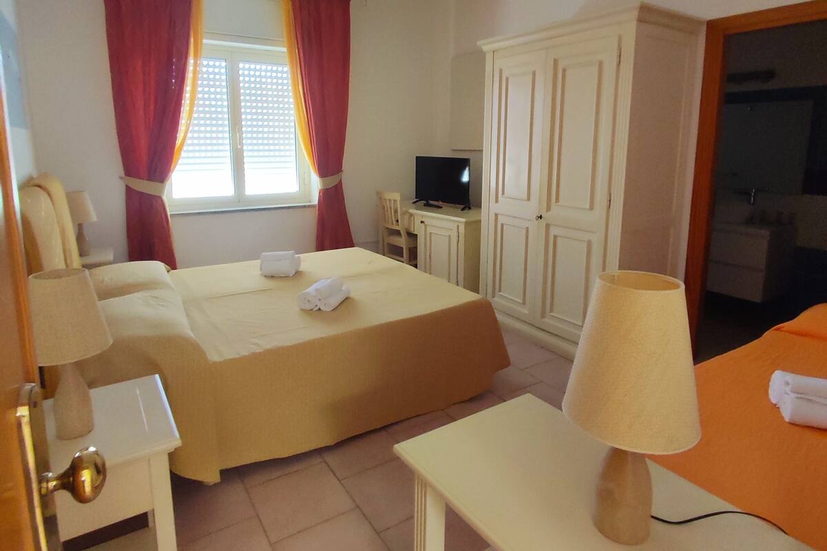 Une chambre d’hôtel avec deux lits, un bureau, une télévision et une armoire.