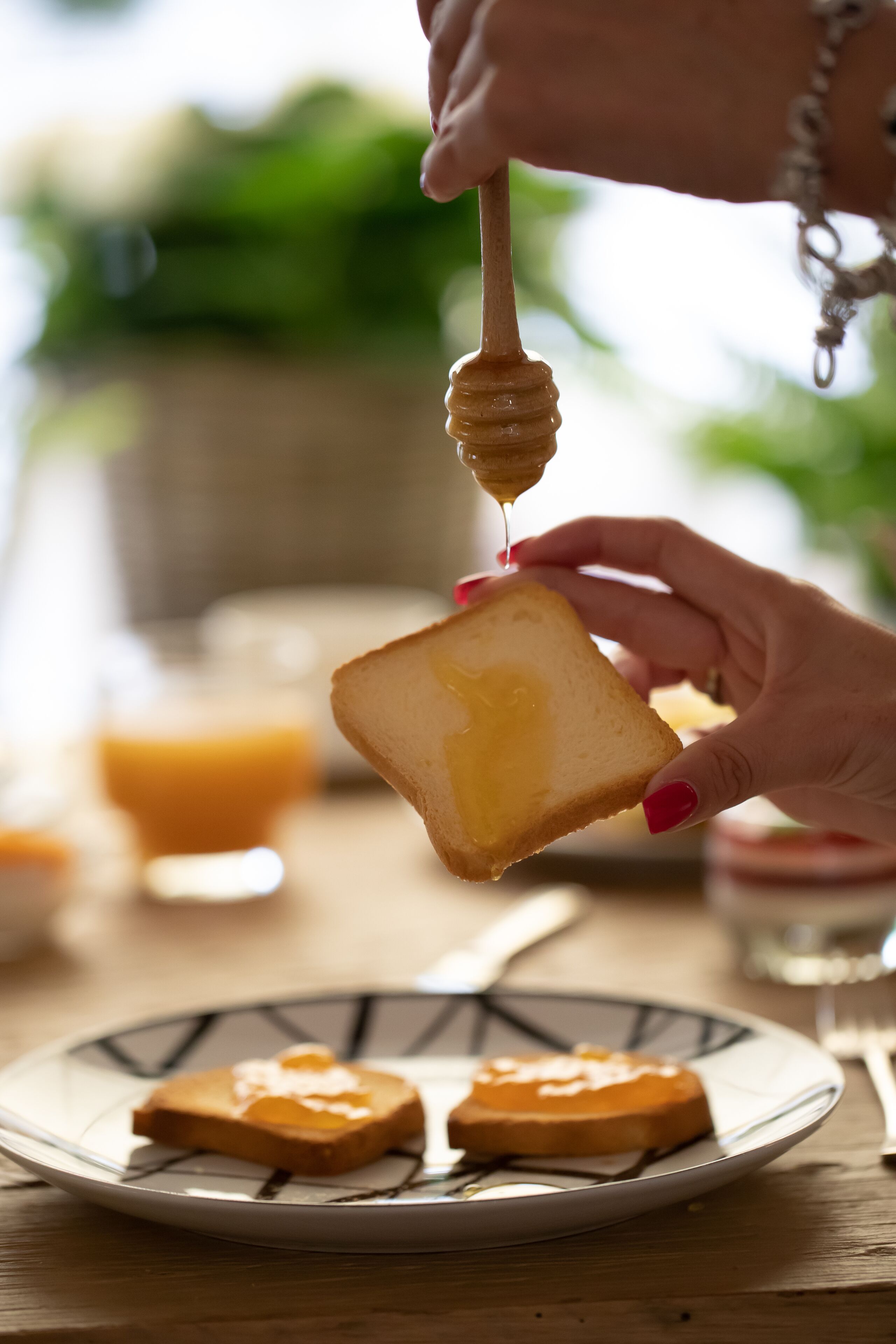Een hand houdt een honinglepel boven toast op een bord.