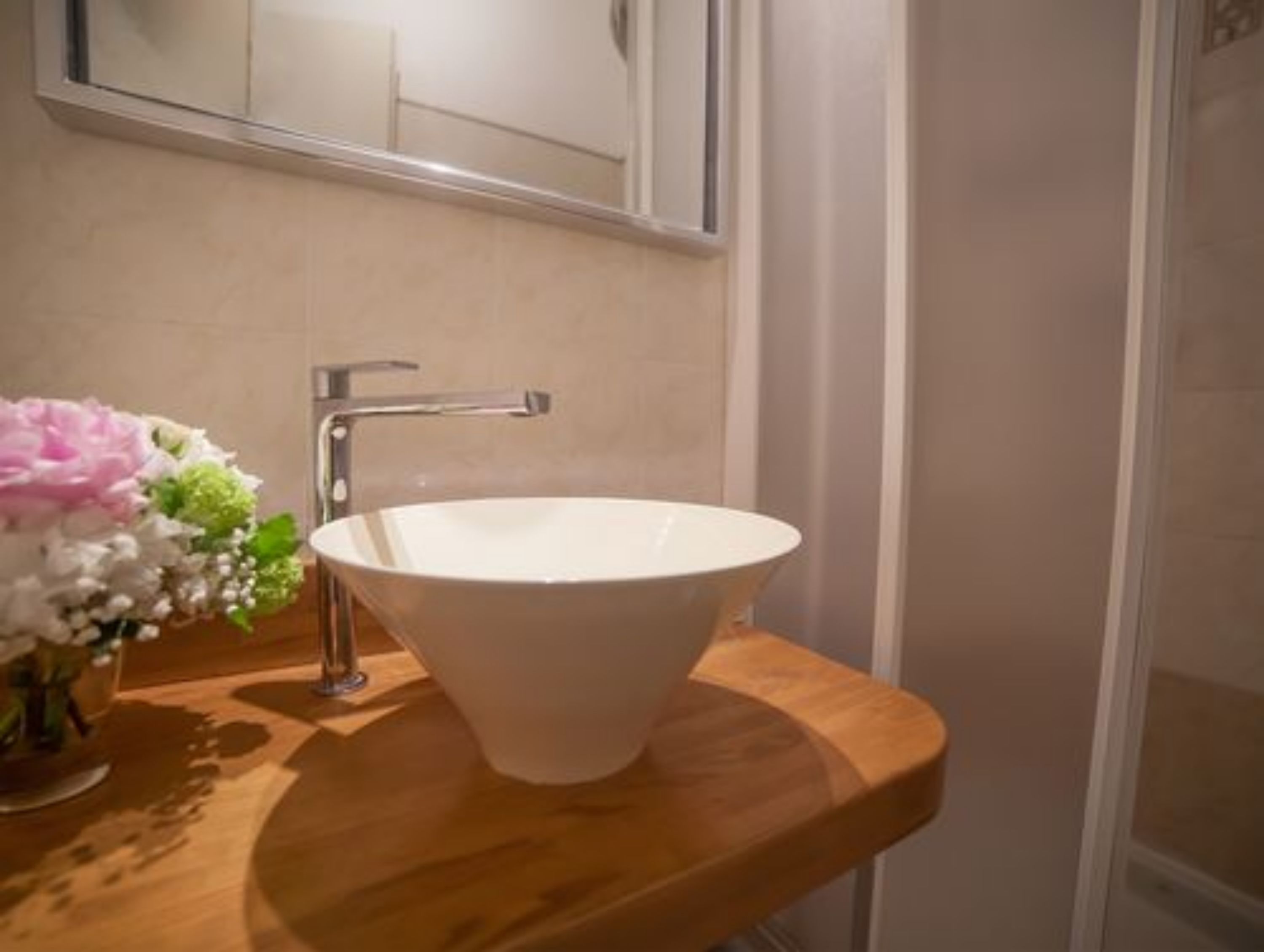 A bathroom with a white sink, wooden countertop, and a mirror above the sink.