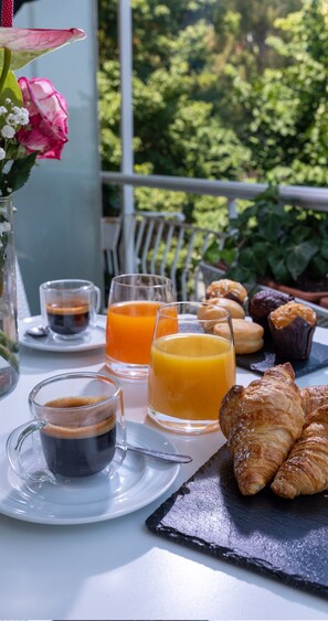A breakfast setting with croissants, orange juice, and coffee on a balcony with a view of greenery. - Hotel Tigullio et de Milan (Santa Margherita Ligure)