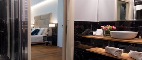 A modern bathroom with a large mirror, a white sink, and a wooden shelf.