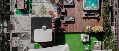 A rooftop garden with a hot tub, outdoor seating, and a pool.