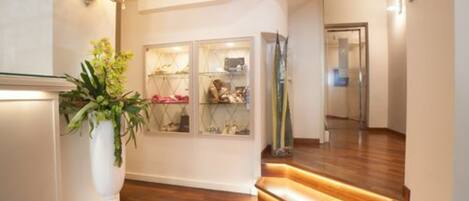 A modern hallway with wooden flooring, a white wall, and a glass display case.