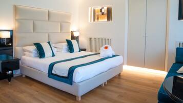 Una habitación de hotel moderna con una cama grande, mesitas de noche, un radiador y una zona de estar con una silla.