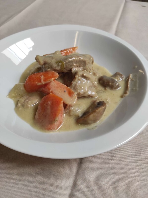 A white plate with a creamy dish containing meat and vegetables.