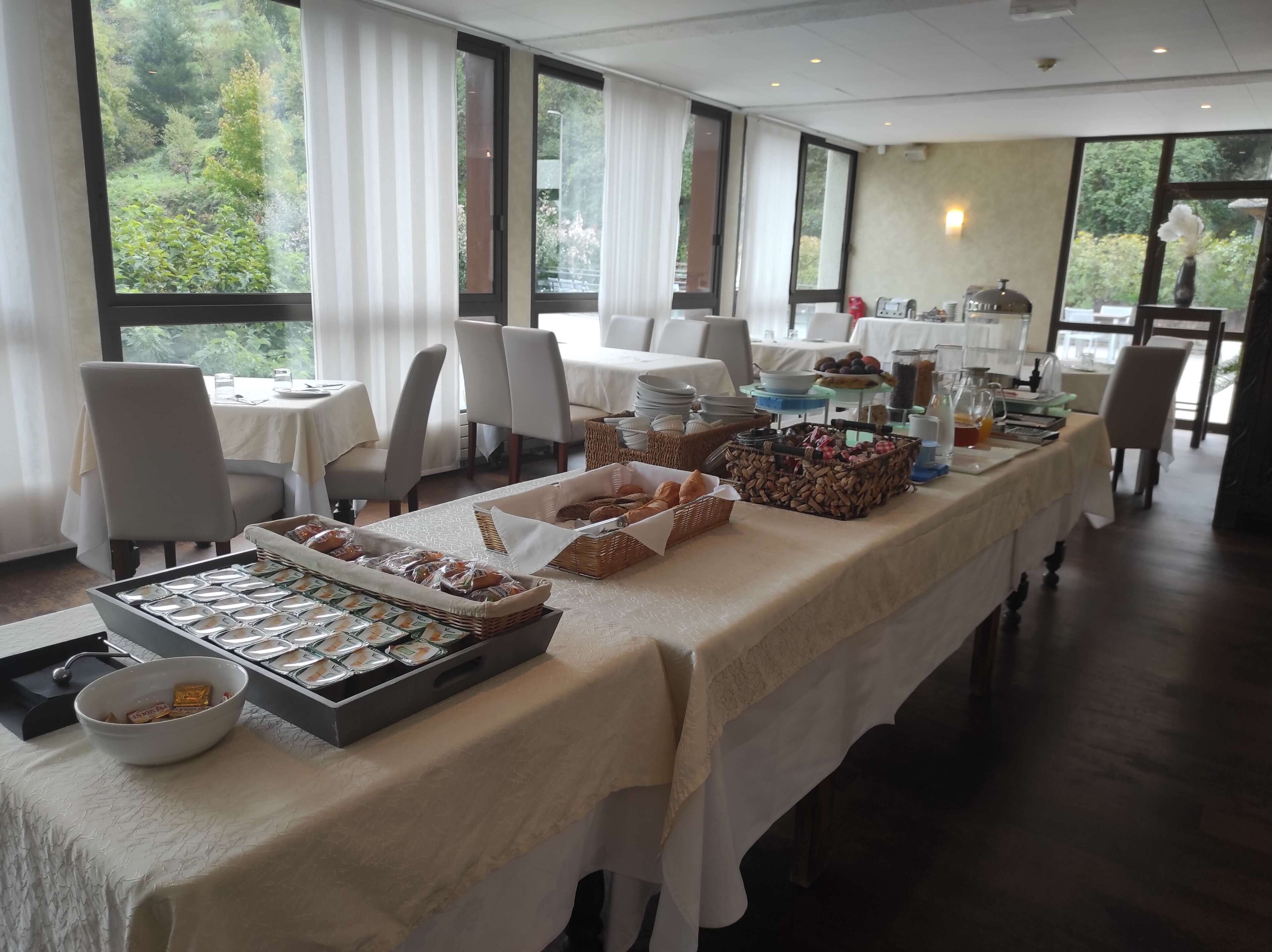 A buffet setup with various food items and a view of greenery outside.