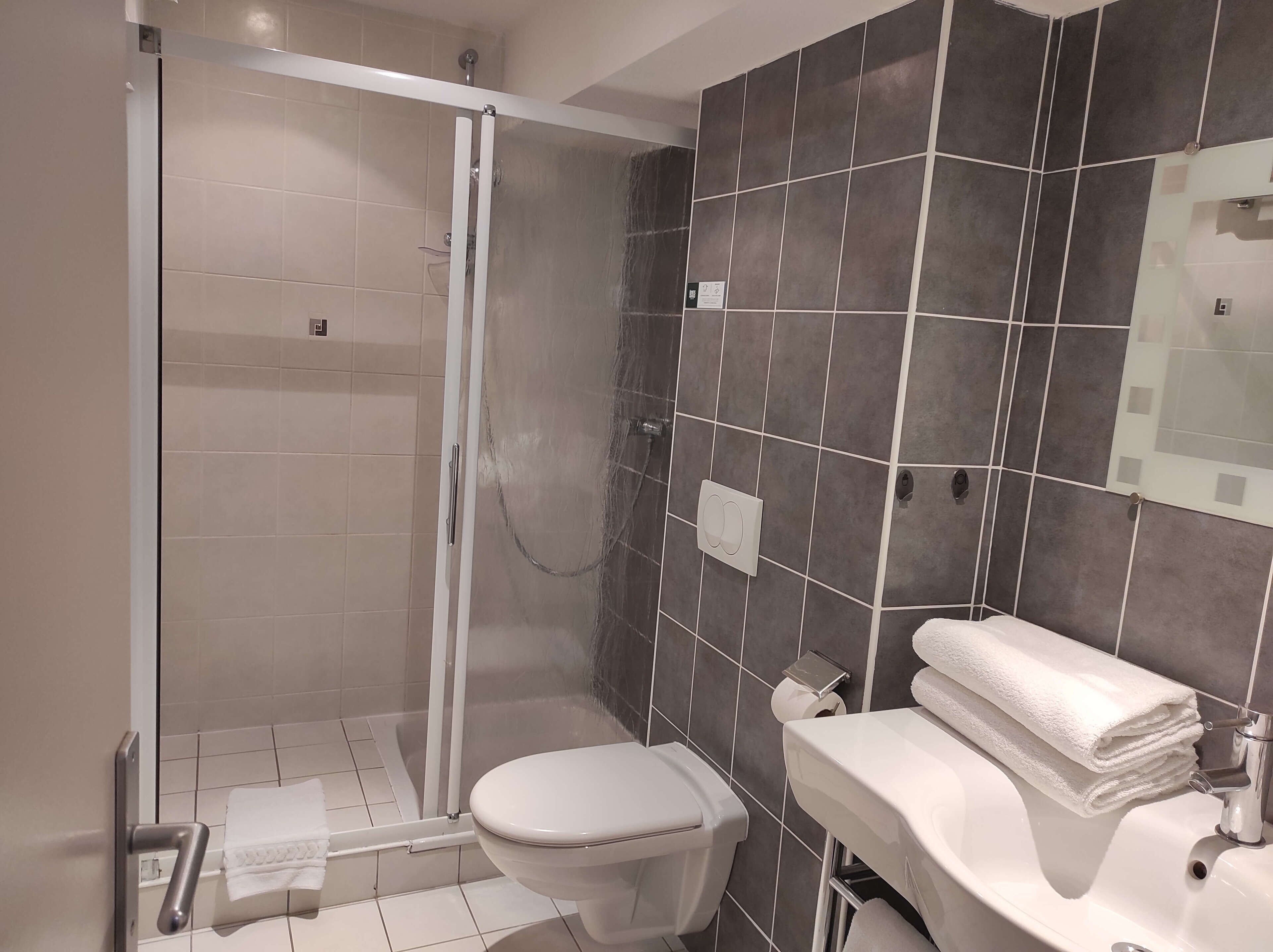 Une salle de bain avec douche, toilettes et lavabo.