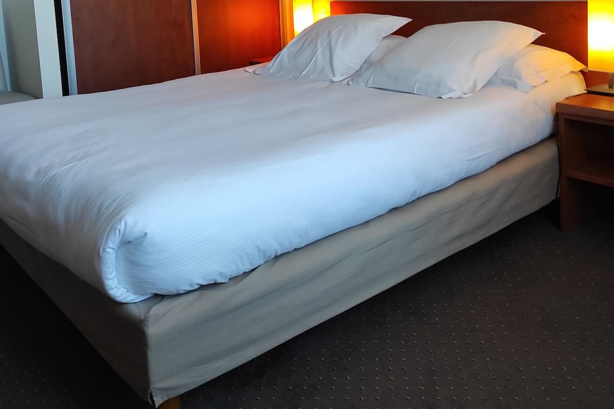 Una cama bien hecha con sábanas blancas en una habitación de hotel.