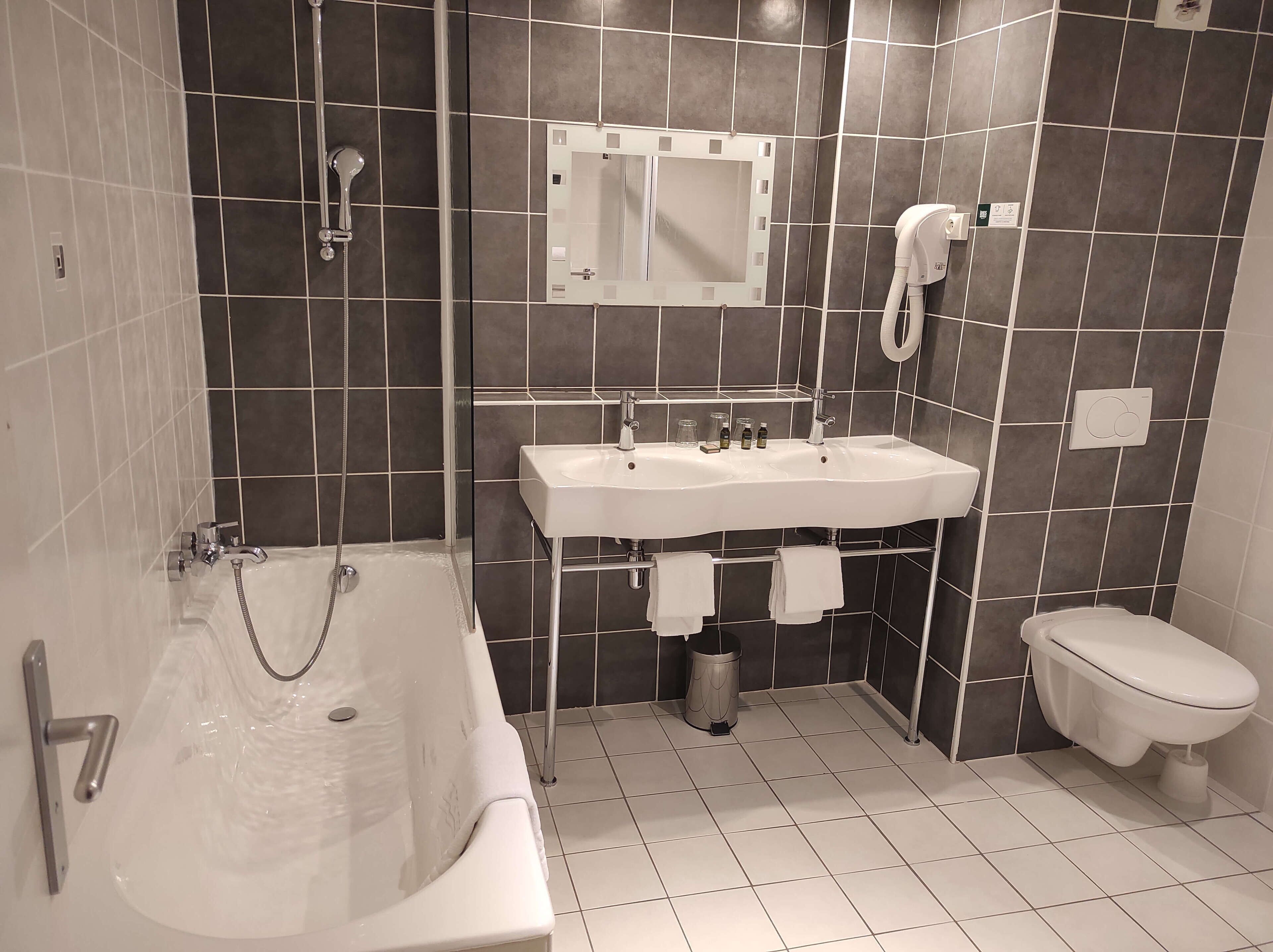 Un baño moderno con bañera, lavamanos, inodoro y espejo.