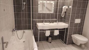 Un baño moderno con bañera, lavamanos, inodoro y espejo.