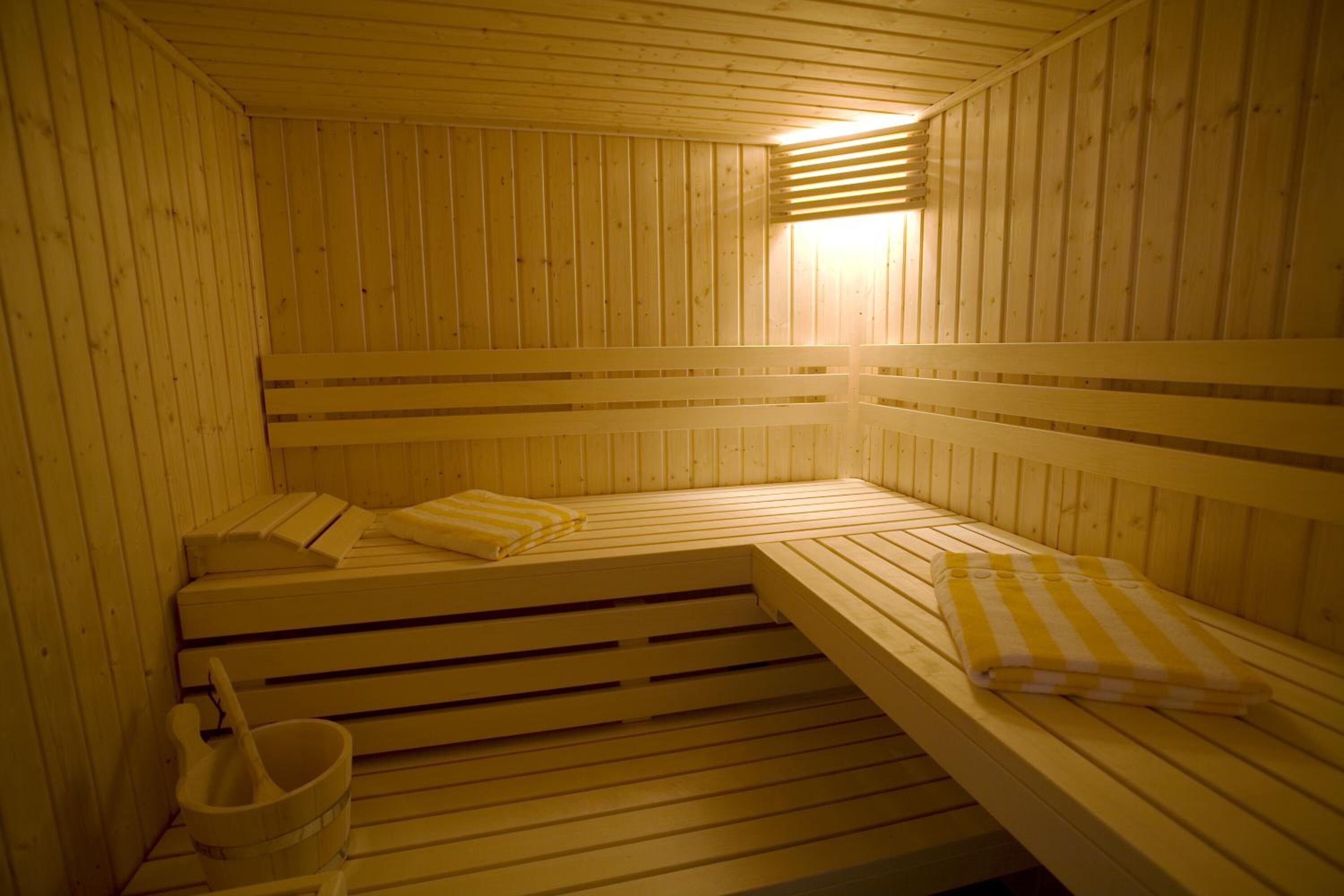 A wooden sauna with benches and a bucket.