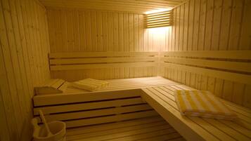 A wooden sauna with benches and a bucket.
