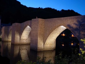 Eine Steinbrücke mit mehreren Bögen, beleuchtet durch künstliches Licht.