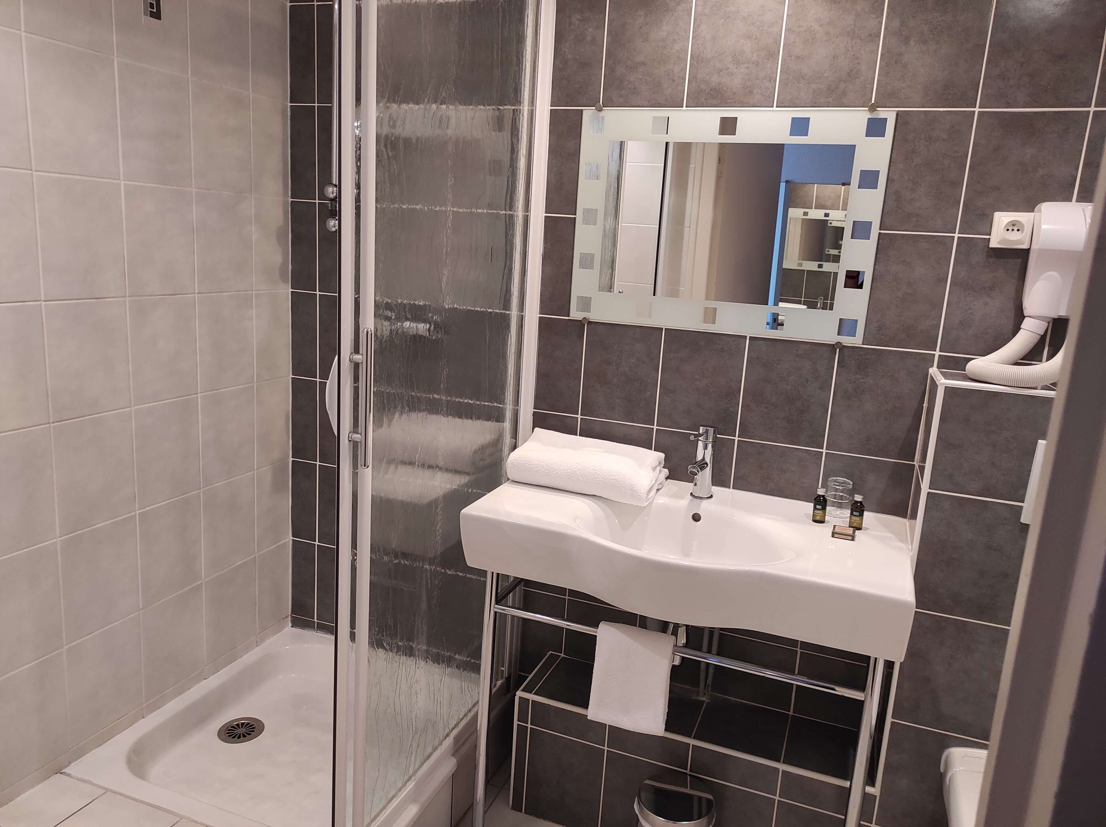 A modern bathroom with a glass-enclosed shower, a white sink with a mirror above it, and a toilet.